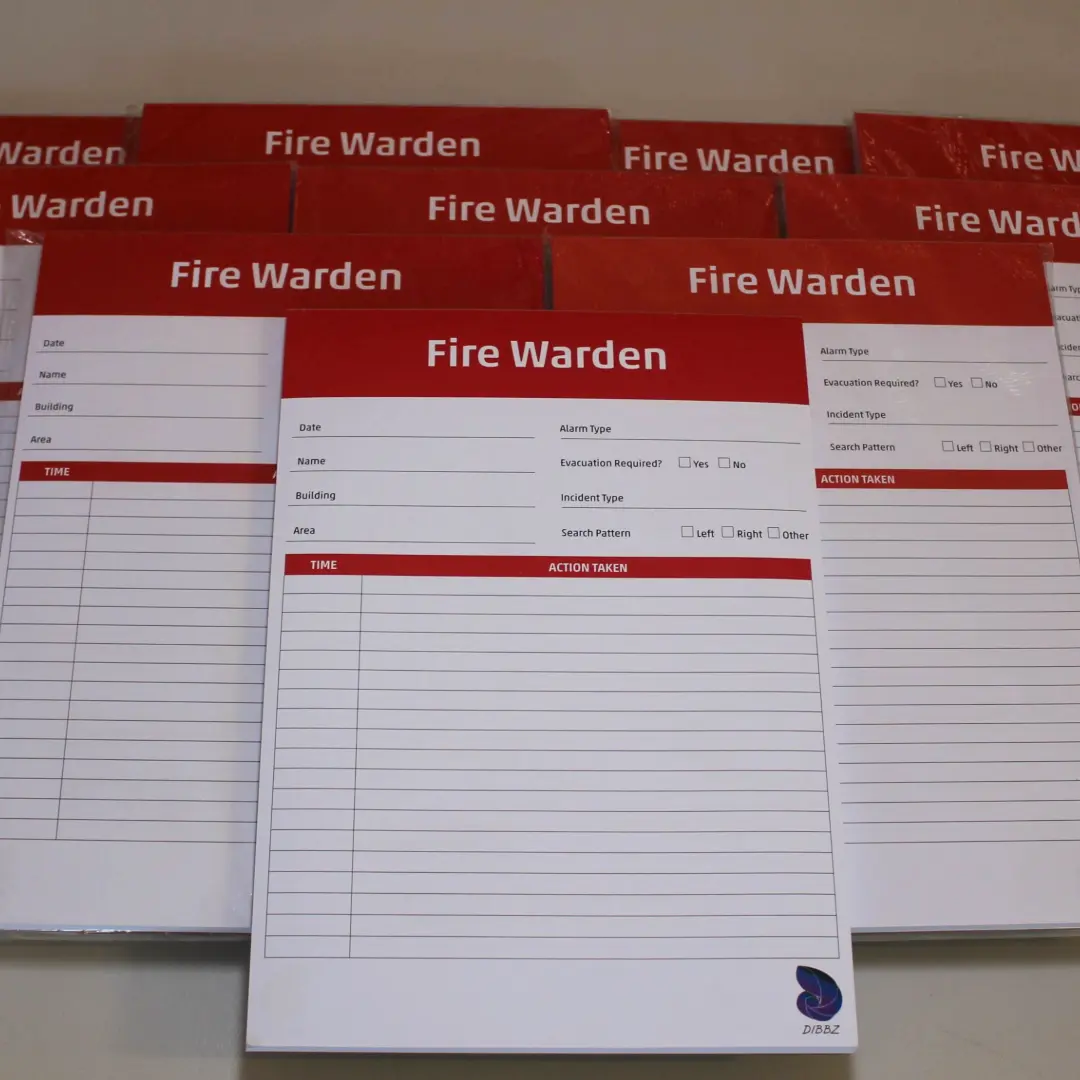 A collection of red Fire Warden evacuation checklist pads laid out together on a neutral background.