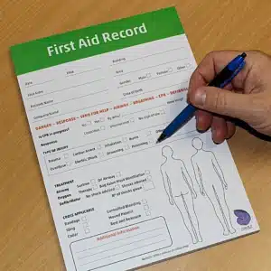 A first aider holding the First Aid Record pad, showing scale and professional paper quality.